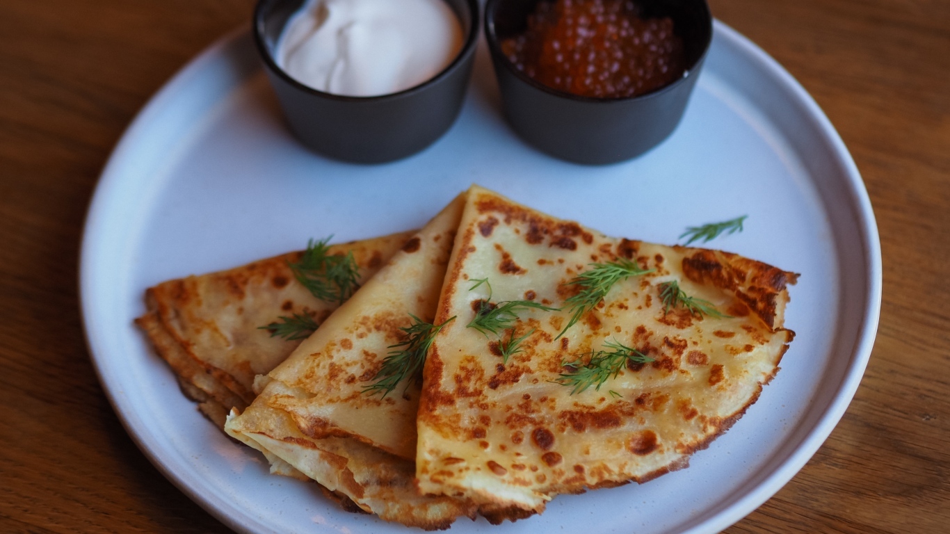 Тонкие блинчики на тарелке с красной икрой и сметаной