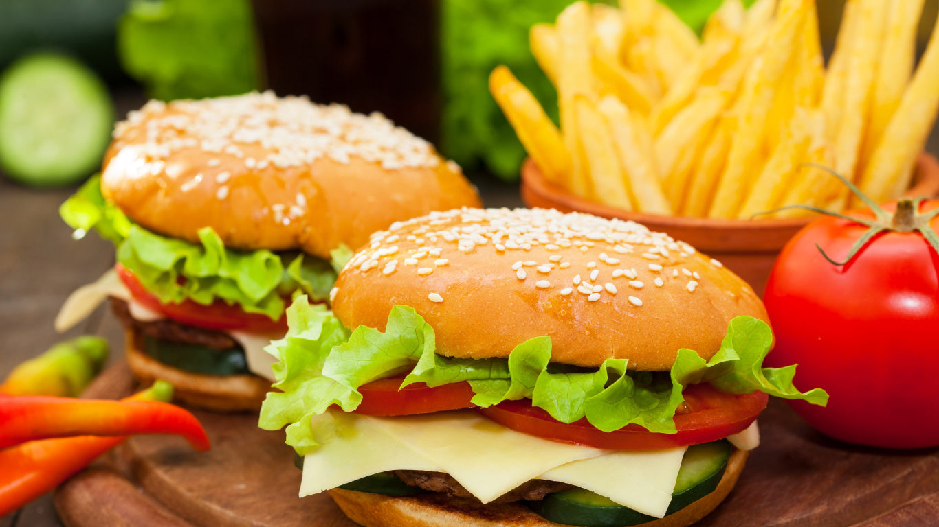 Два больших гамбургера на столе с картофелем фри