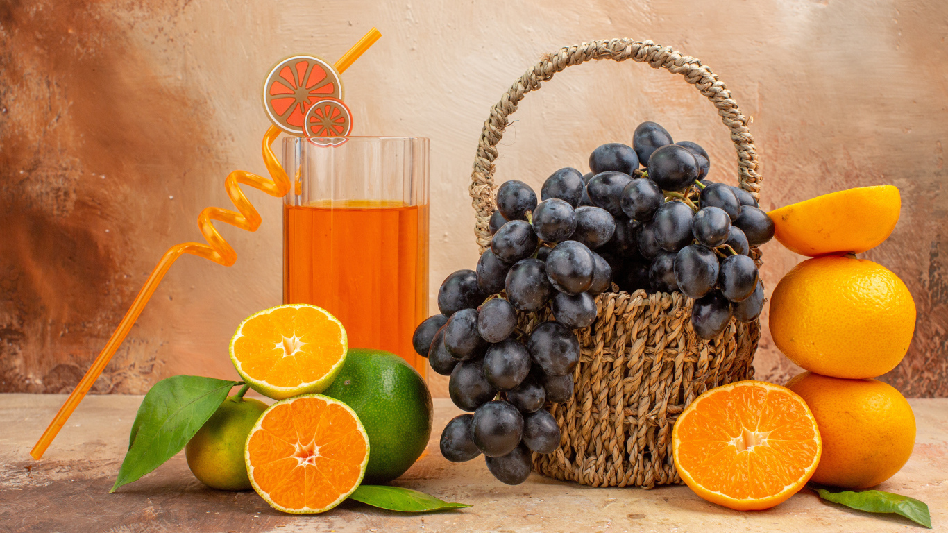 Корзина с виноградом на столе с апельсинами и лаймом