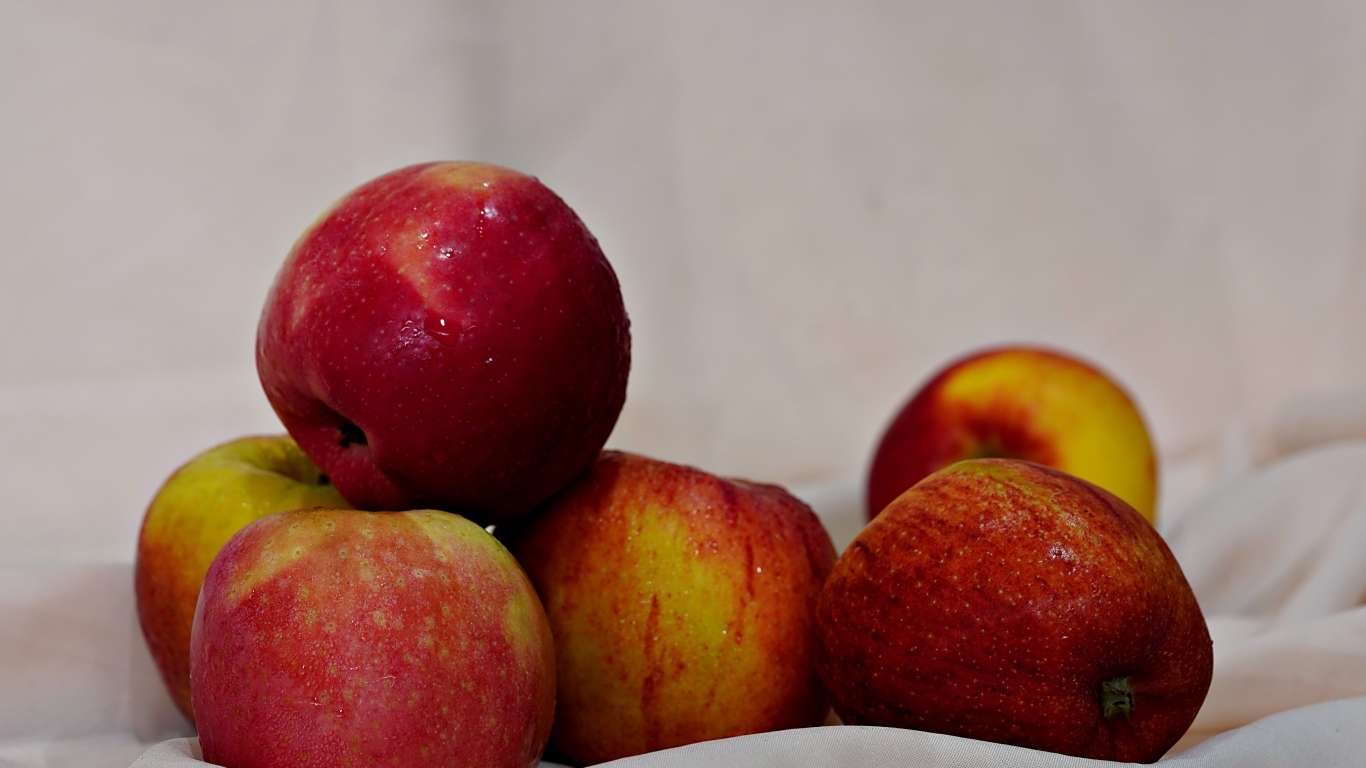 Много красных яблок с белой тканью 