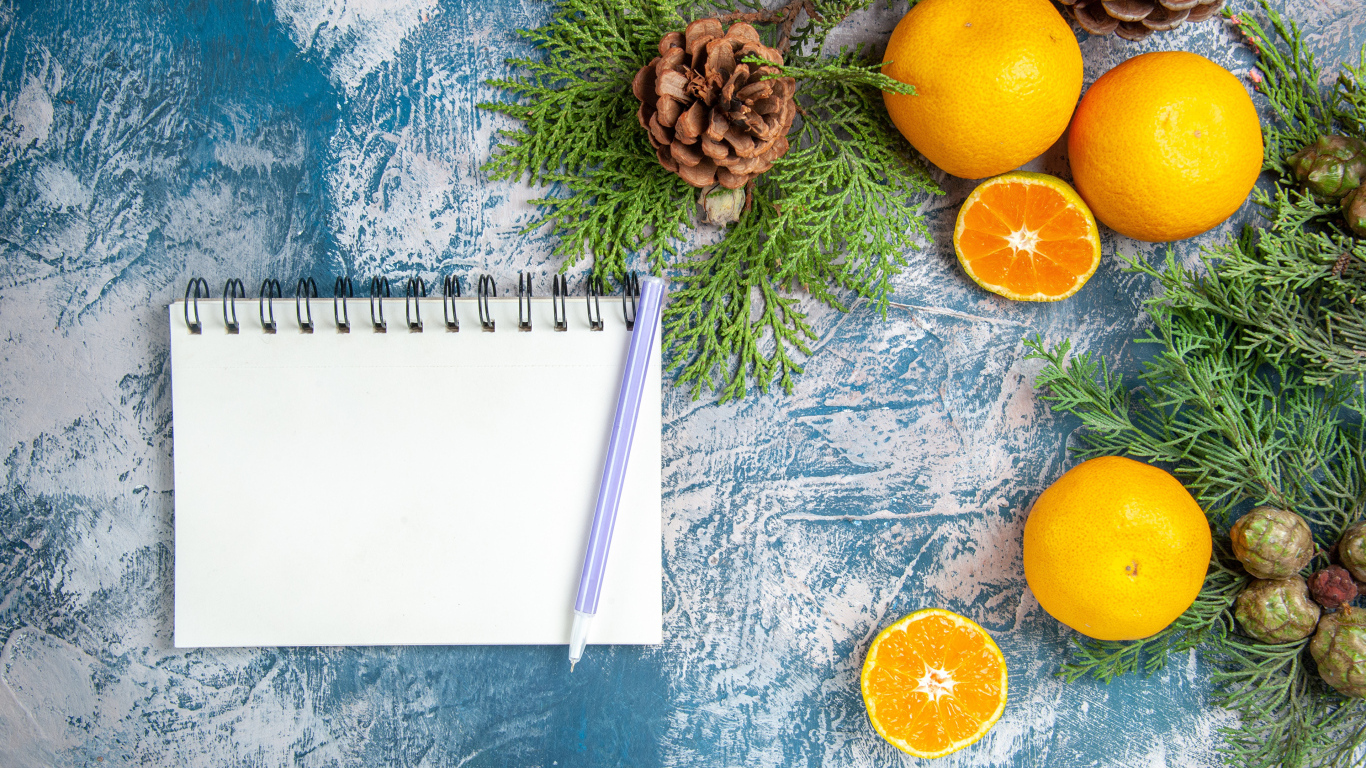 Блокнот на столе с мандаринами и ветками