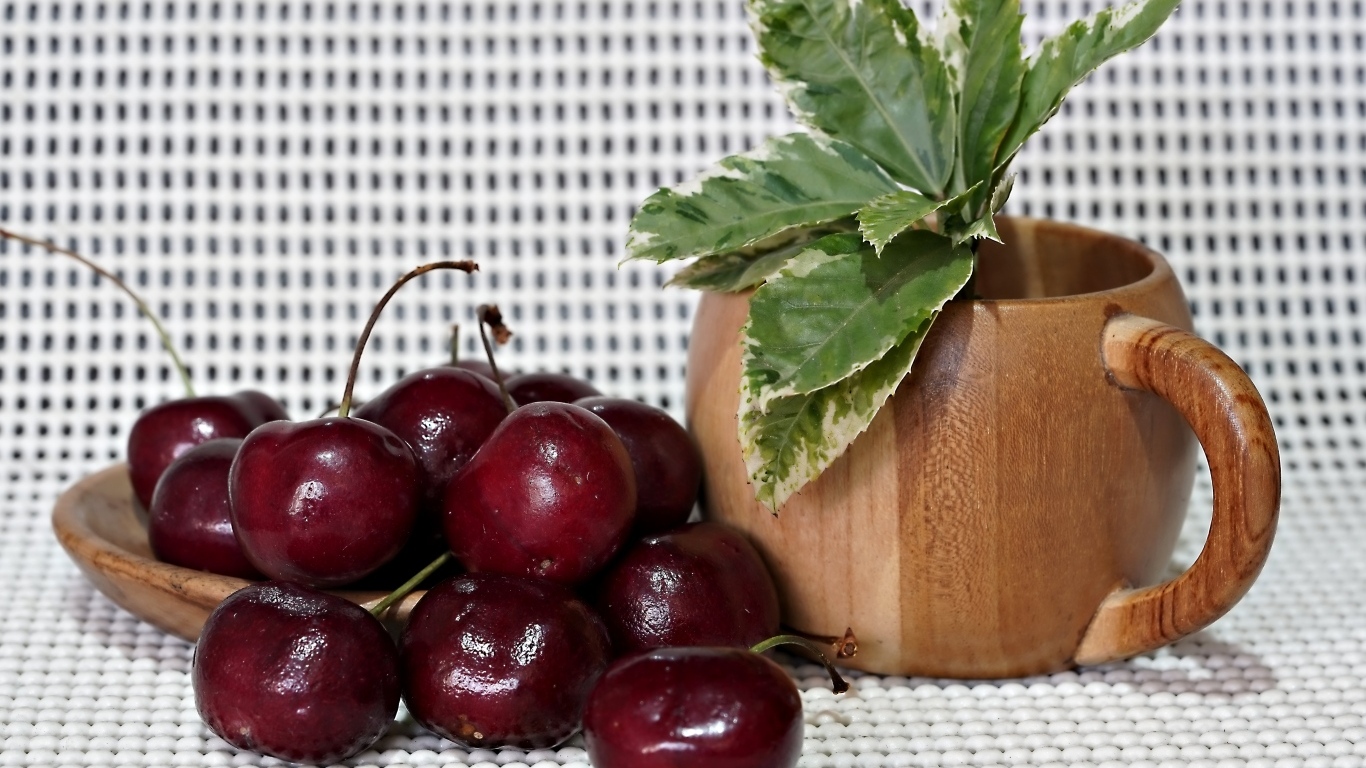 Спелые красные черешни на столе с цветком