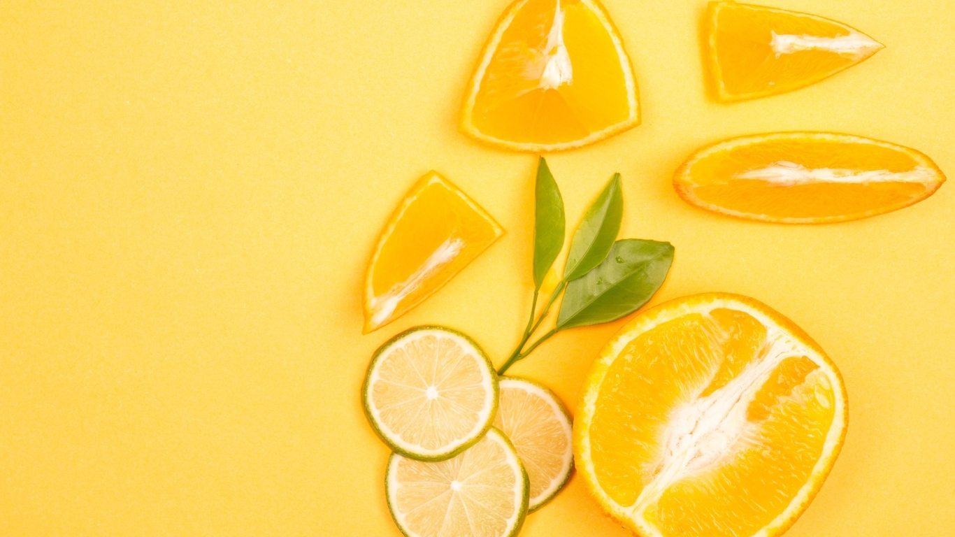 Нарезанные плоды апельсина и лайма на желтом фоне