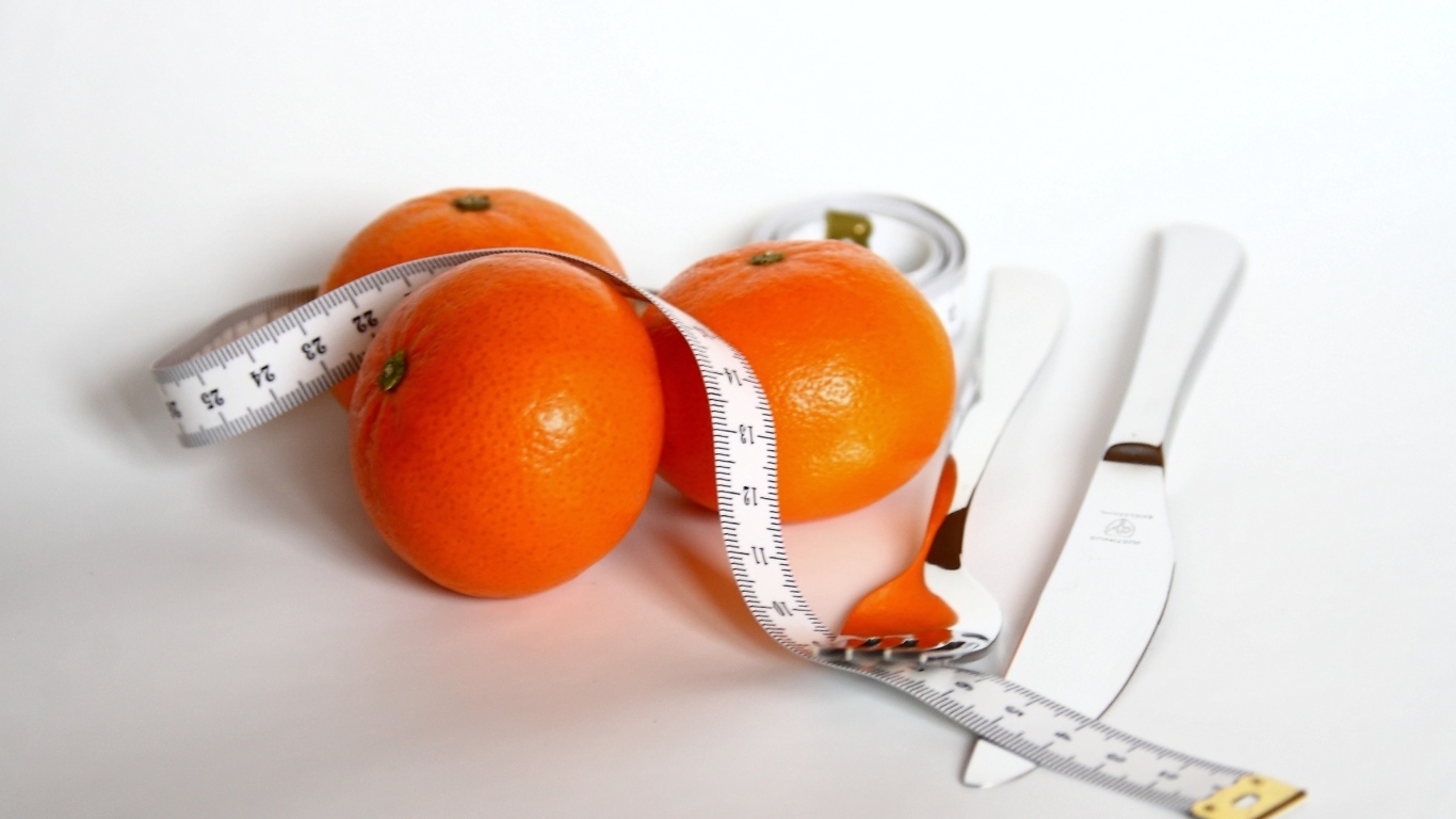 Мандарины с сантиметром и столовыми приборами на белом фоне