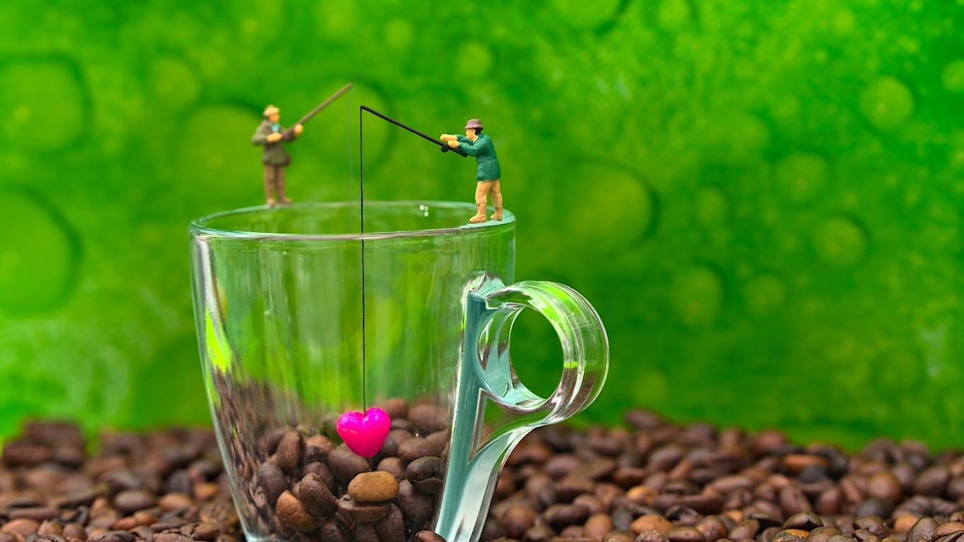 Две фигурки на стеклянной чашкой с кофейными зернами