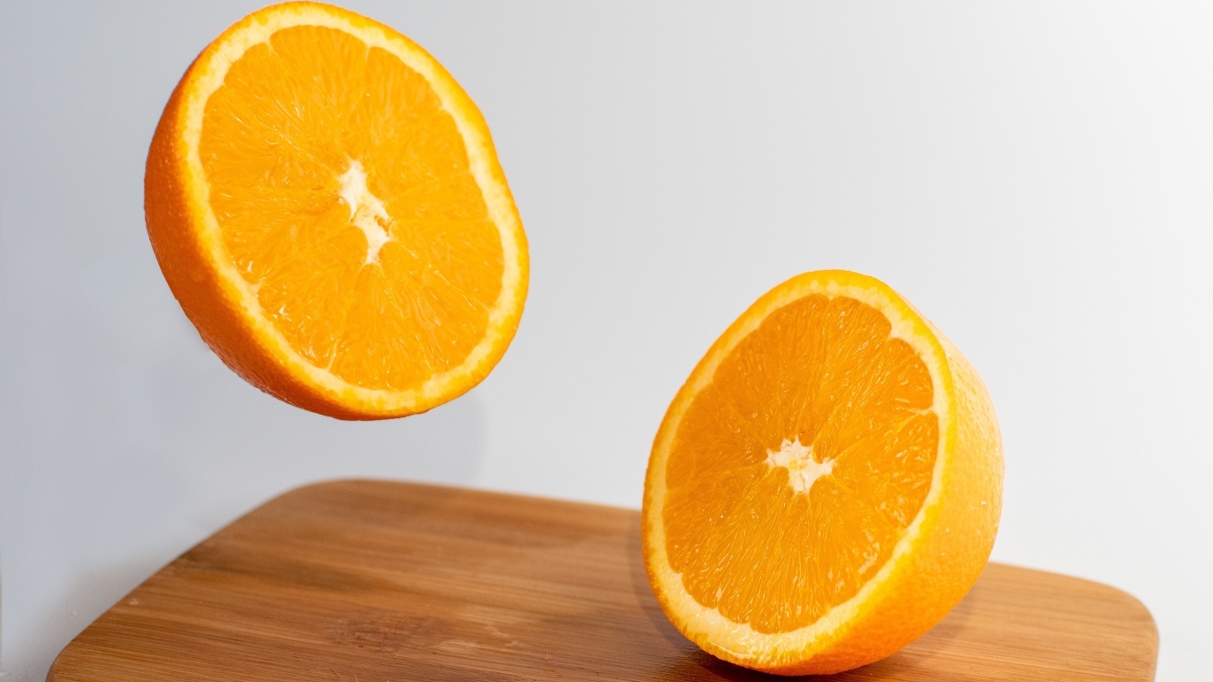 Две половинки апельсина на деревянной доске