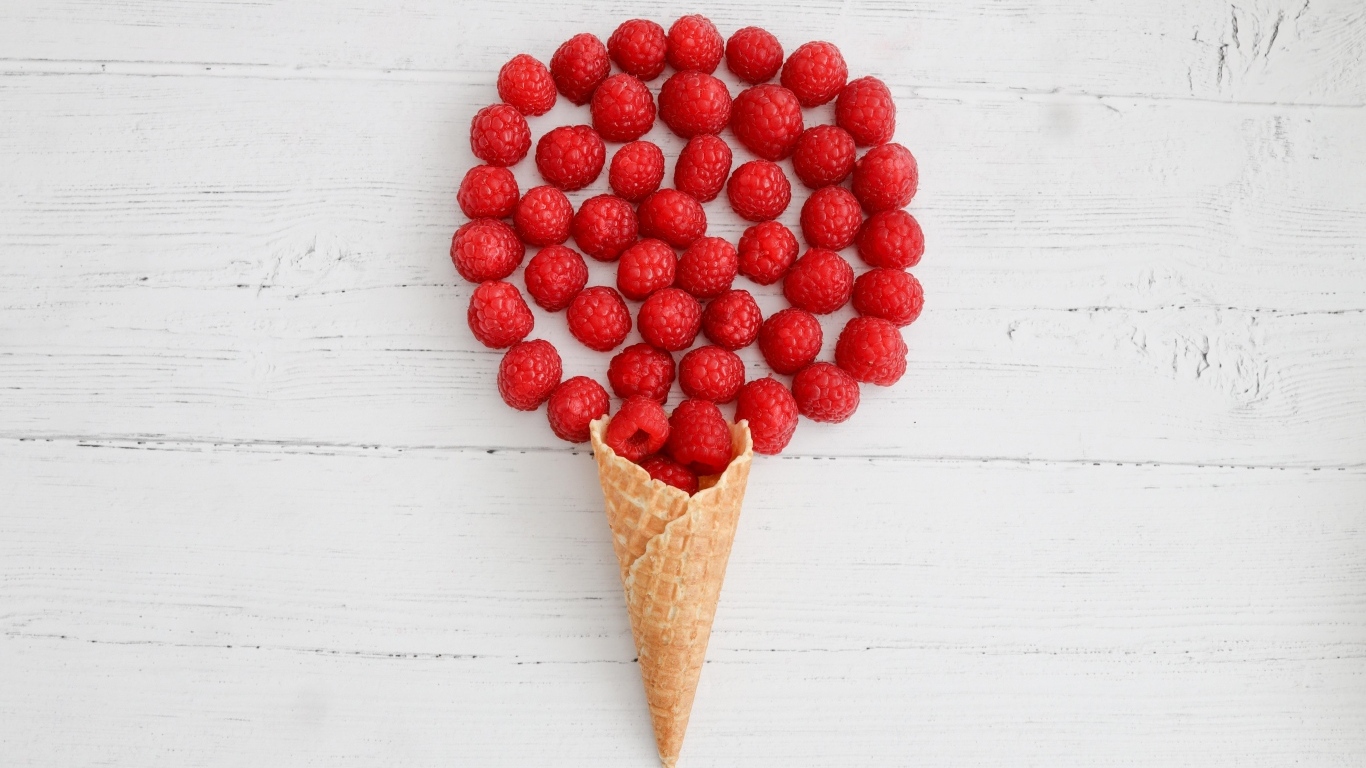 Вафельный рожок с ягодами малины на белом столе