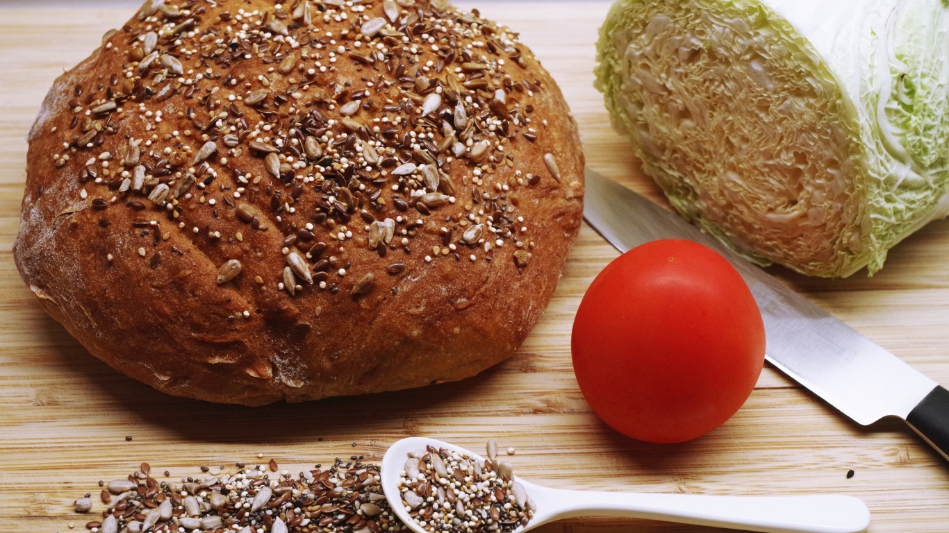 Буханка хлеба на столе с капустой и помидором