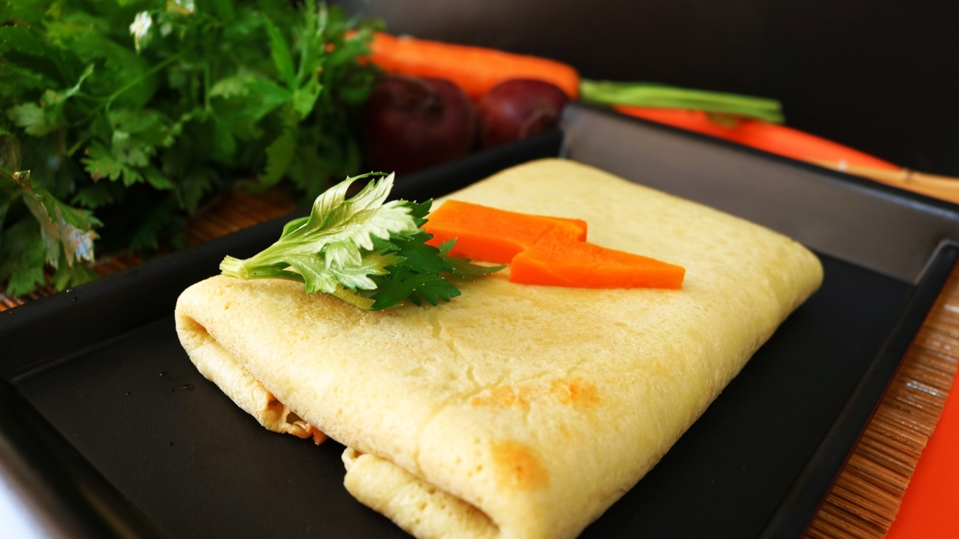 Блинчик на тарелке с морковью и веточками петрушки