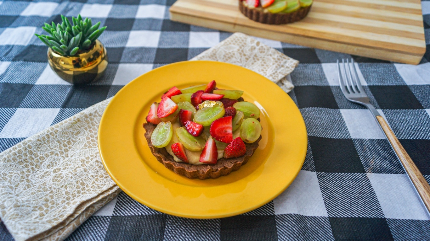 Пирожное с кремом и ягодами клубники и винограда