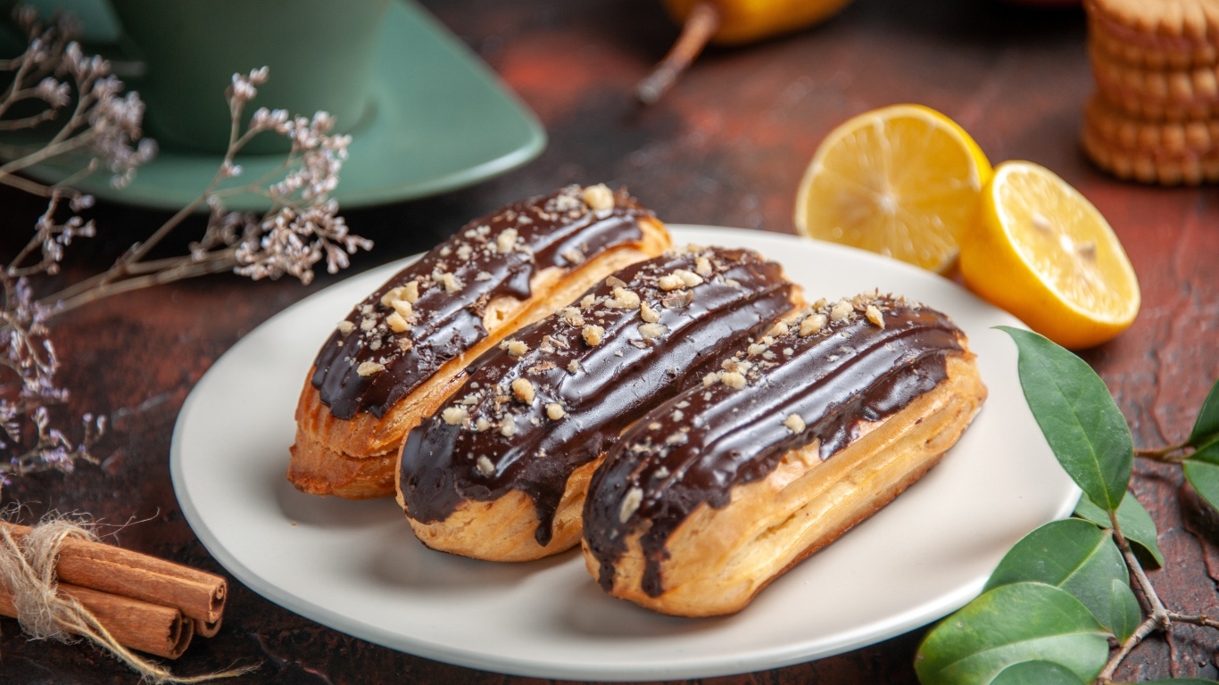 Эклеры на тарелке с корицей и апельсинами