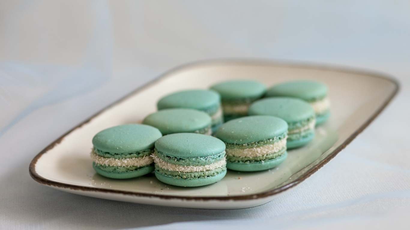 Зеленый десерт макаронс на большой тарелке на столе