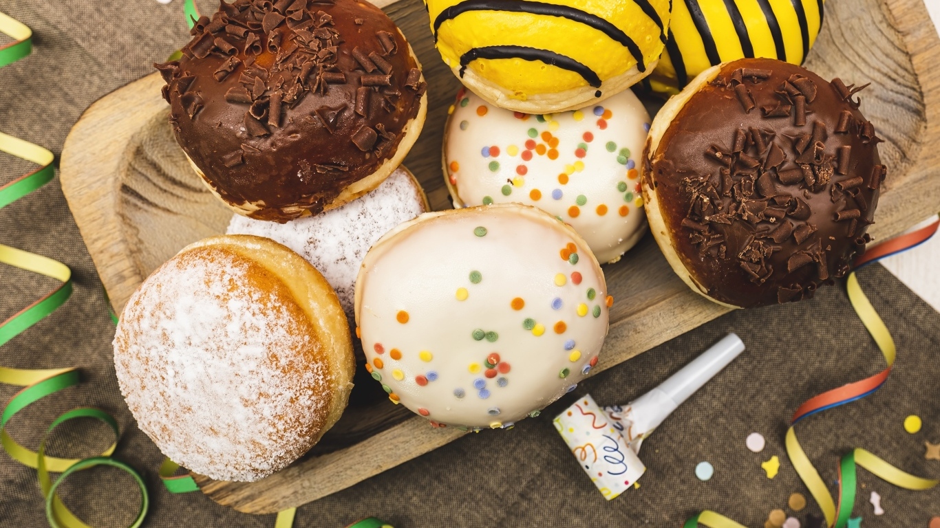 Много сладких пончиков в глазури на столе