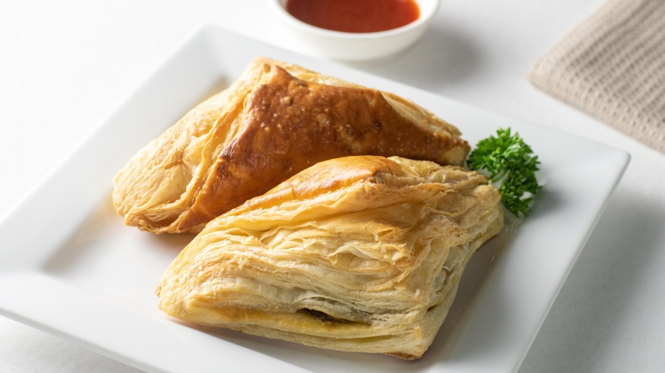 Слоеная выпечка на белой тарелке с соусом