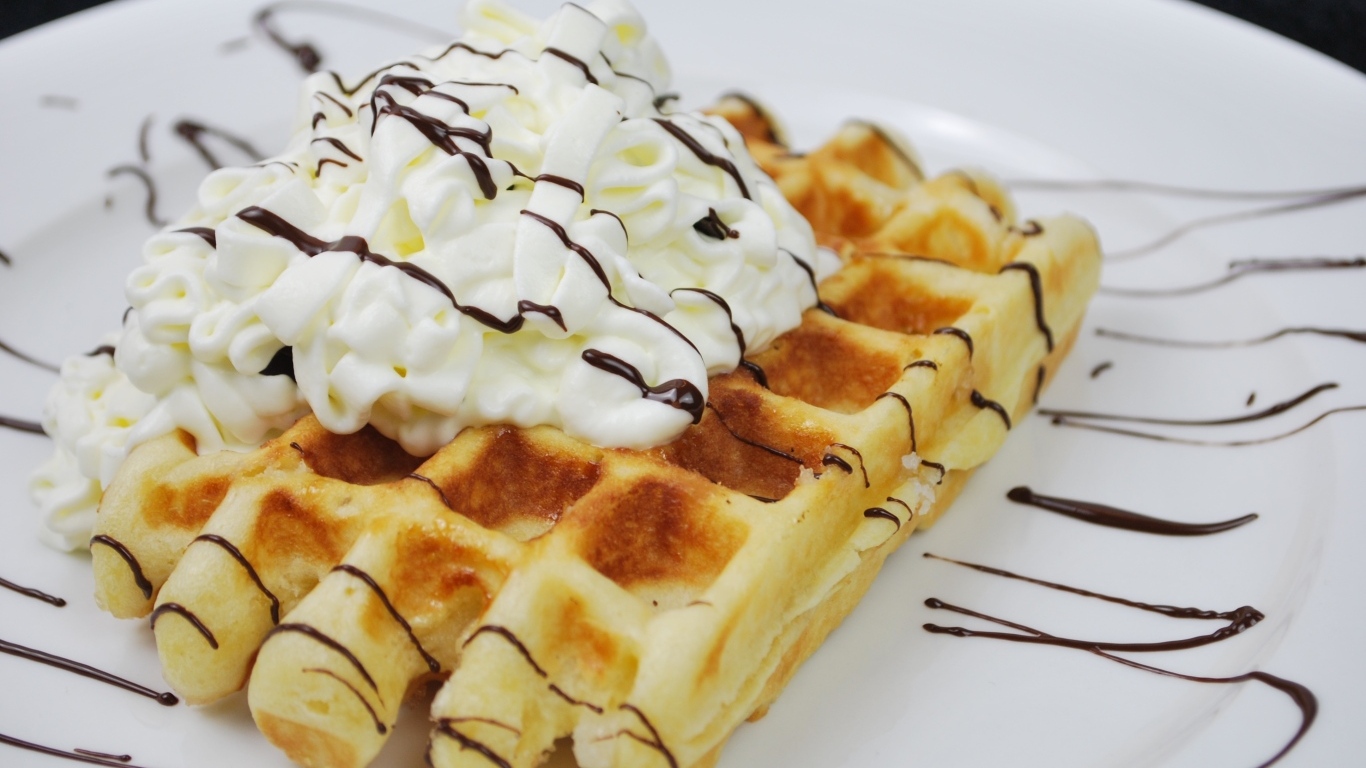 Сладкая вафля со сливками на белой тарелке