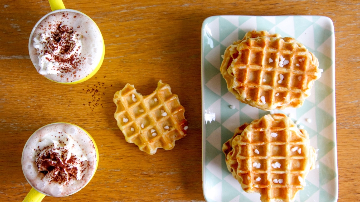 Сладкие вафли на столе с капучино