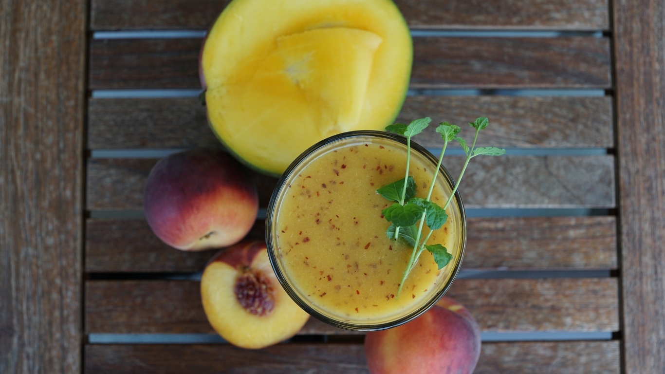 Коктейль с веточкой мяты на столе с фруктами