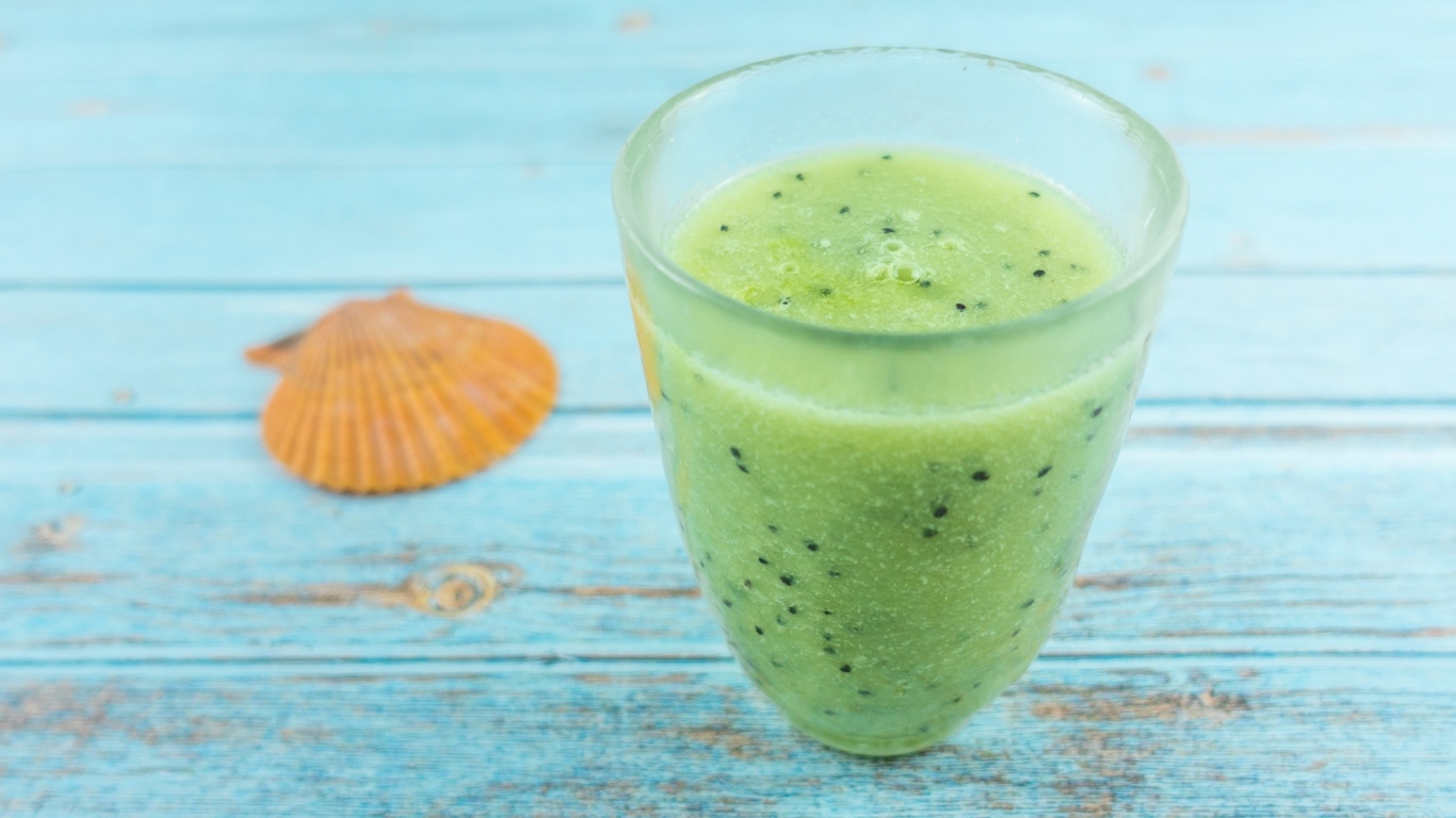 Фруктовый зеленый смузи на голубом столе
