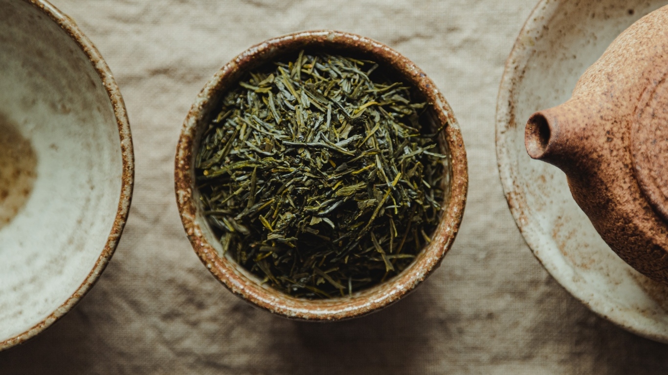 Зеленый чай в пиале на столе с чайником