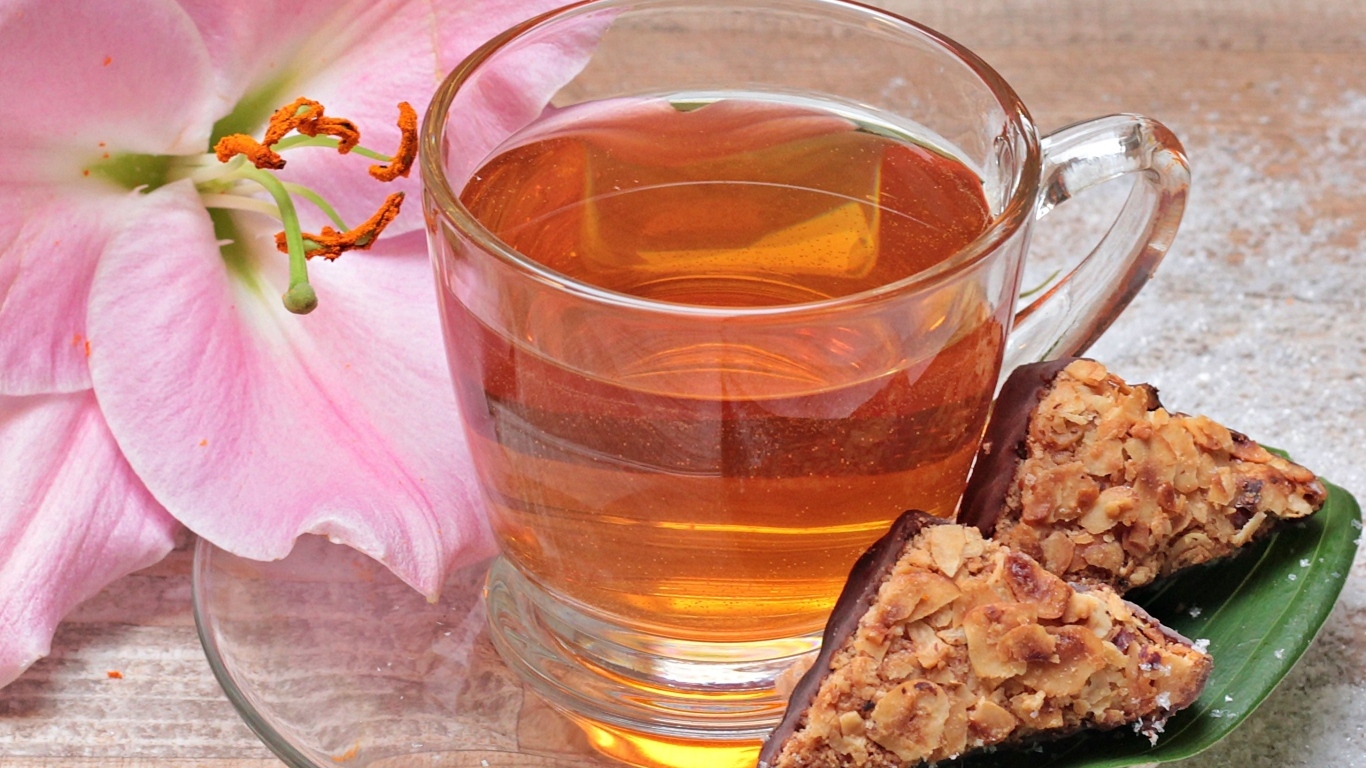 Чай на столе с розовой лилией и конфетами