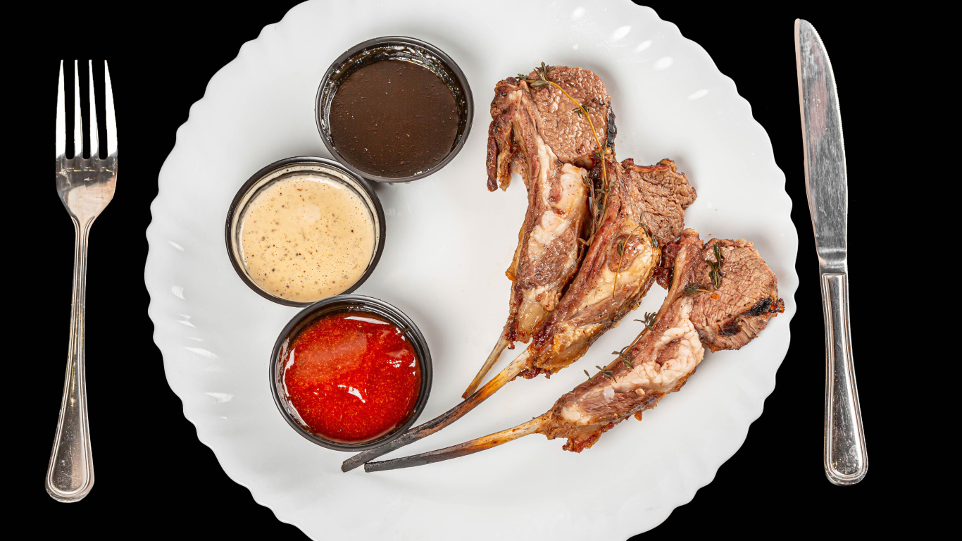 Свиные ребра с соусом на белой тарелке 