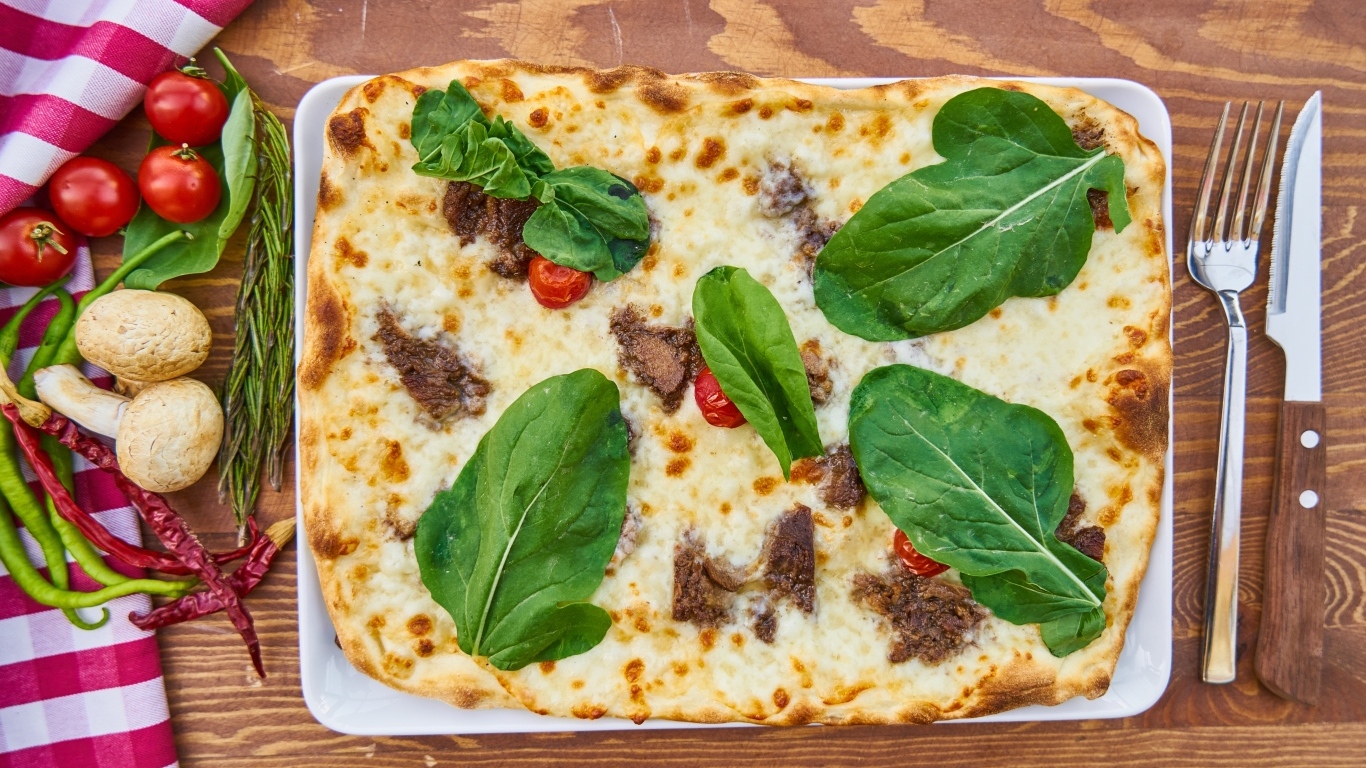 Мясная пицца с сыром и зелеными листьями