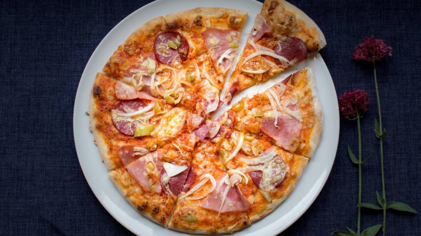 Нарезанная пицца на белой тарелке