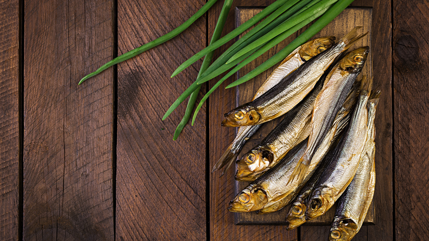 Рыба салака на столе с зеленым луком