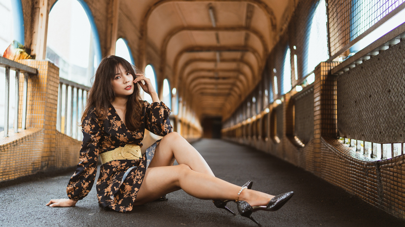 Девушка в красивом коротком платье сидит на полу