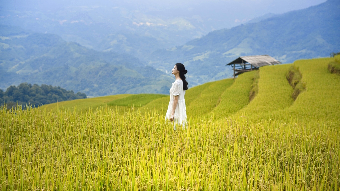 Девушка азиатка в белом платье дышит горным воздухом