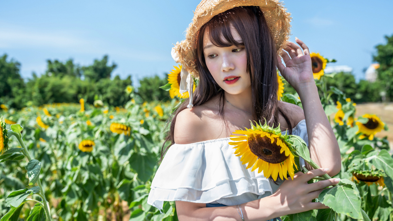 Девушка азиатка на поле с подсолнухами