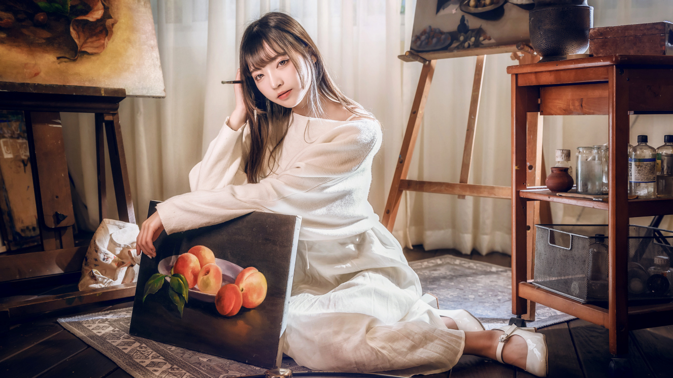 Девушка азиатка сидит с картиной на полу