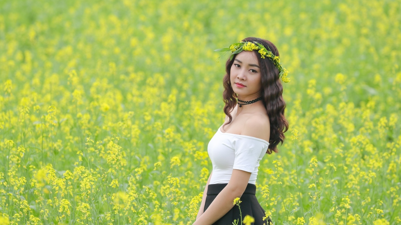 Девушка азиатка стоит на рапсовом поле
