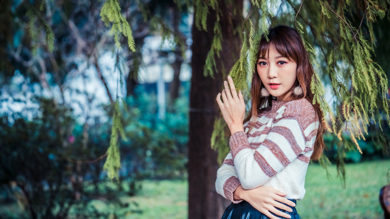 Девушка азиатка стоит у дерева ели