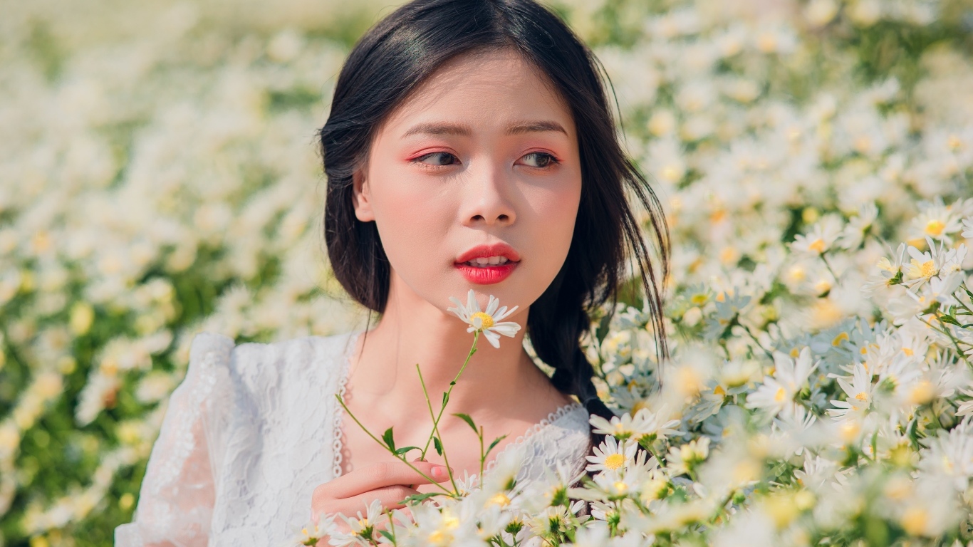 Красивая девушка азиатка на поле с белыми ромашками