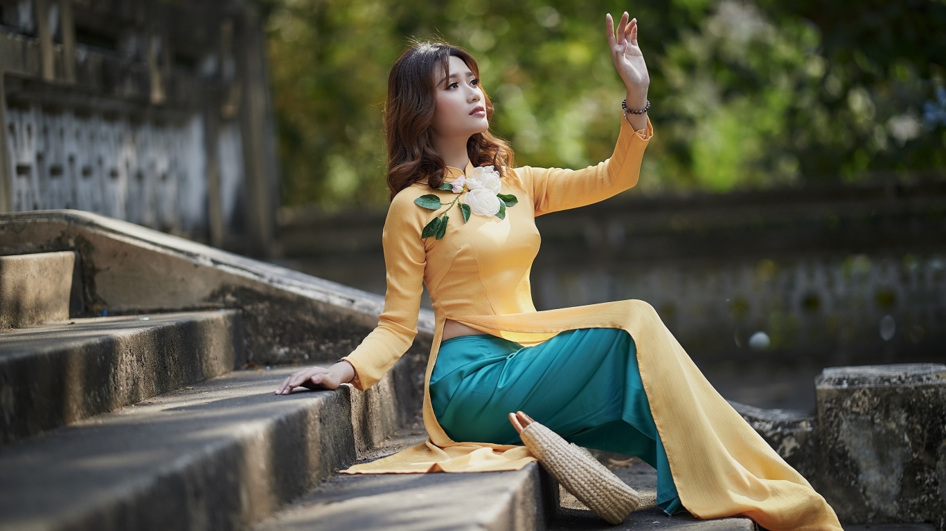 Красивая девушка азиатка сидит на ступеньках