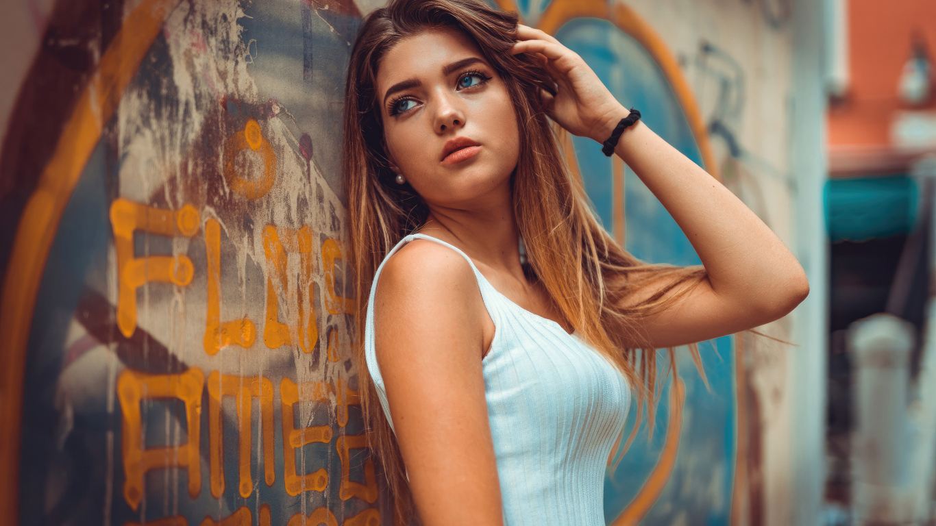 Красивая голубоглазая девушка стоит у стены