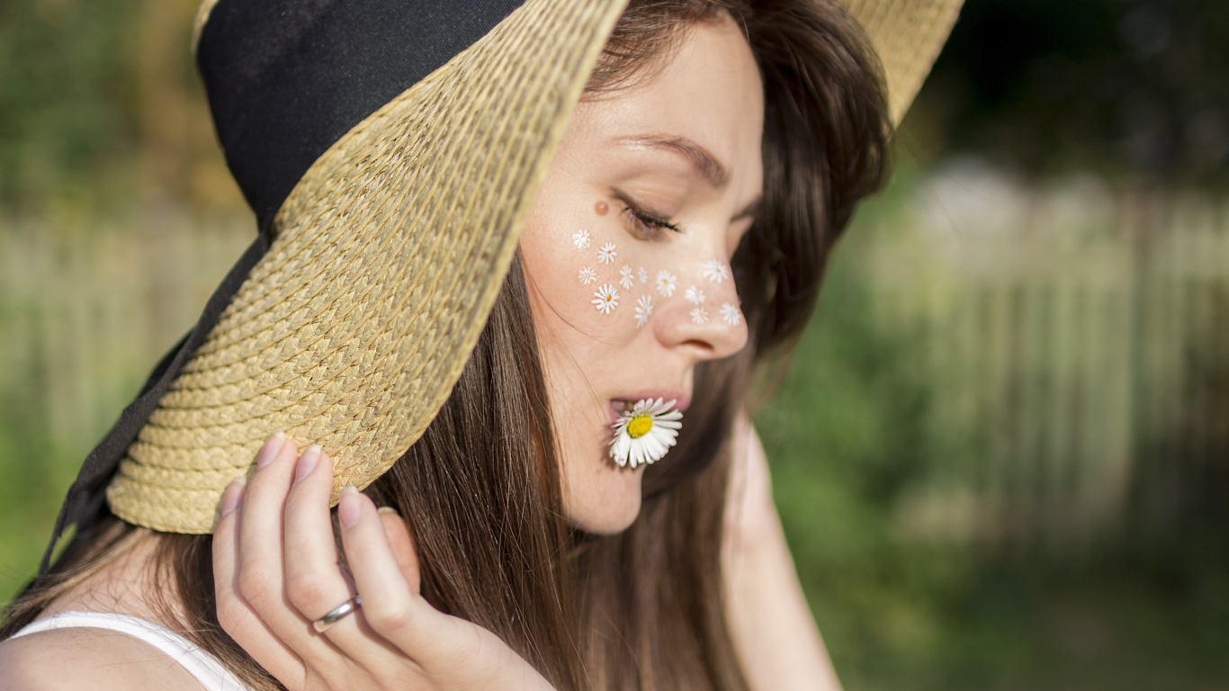 Красивая девушка в соломенной шляпе с ромашкой