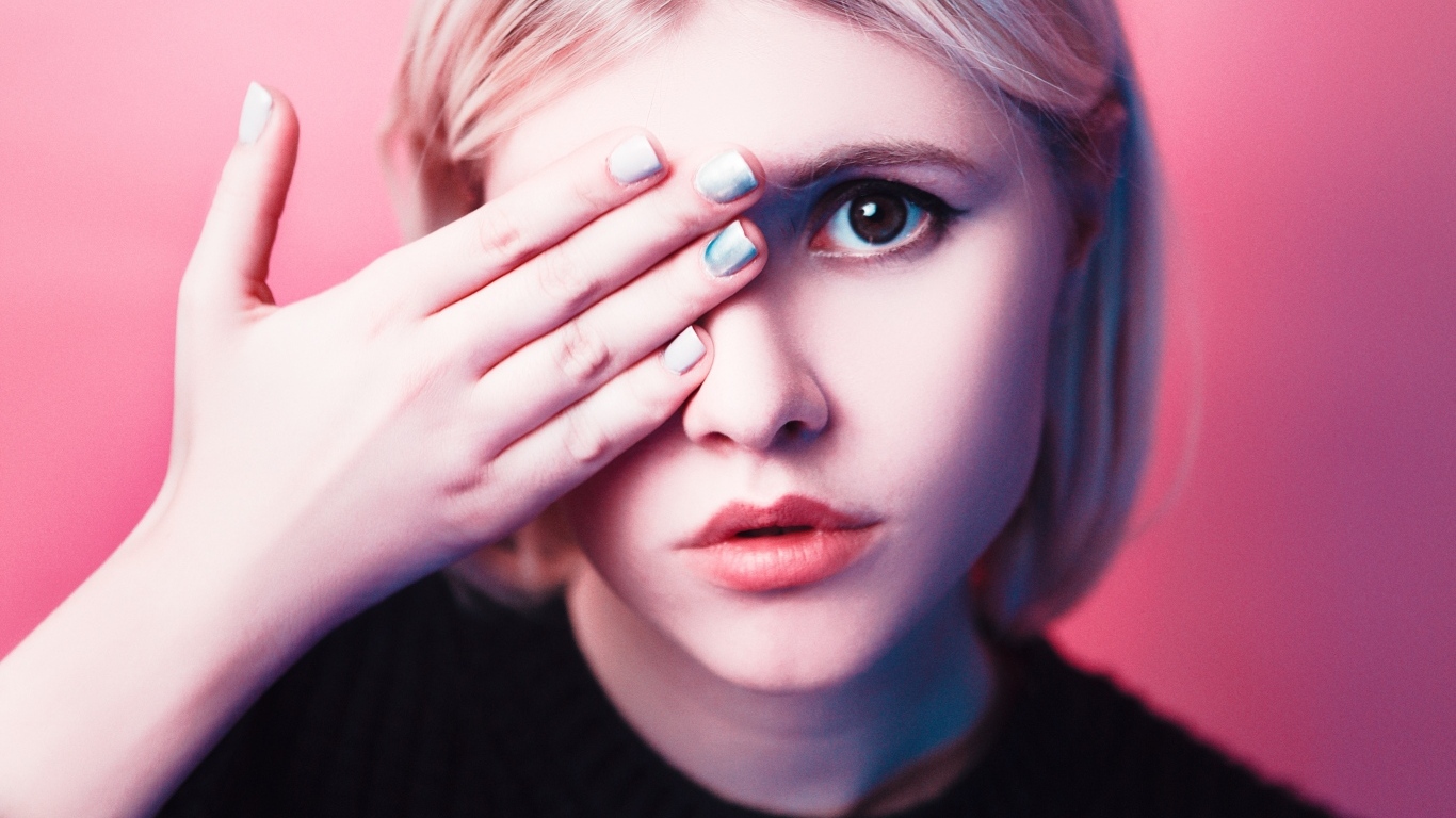 Кареглазая девушка закрыла глаз рукой