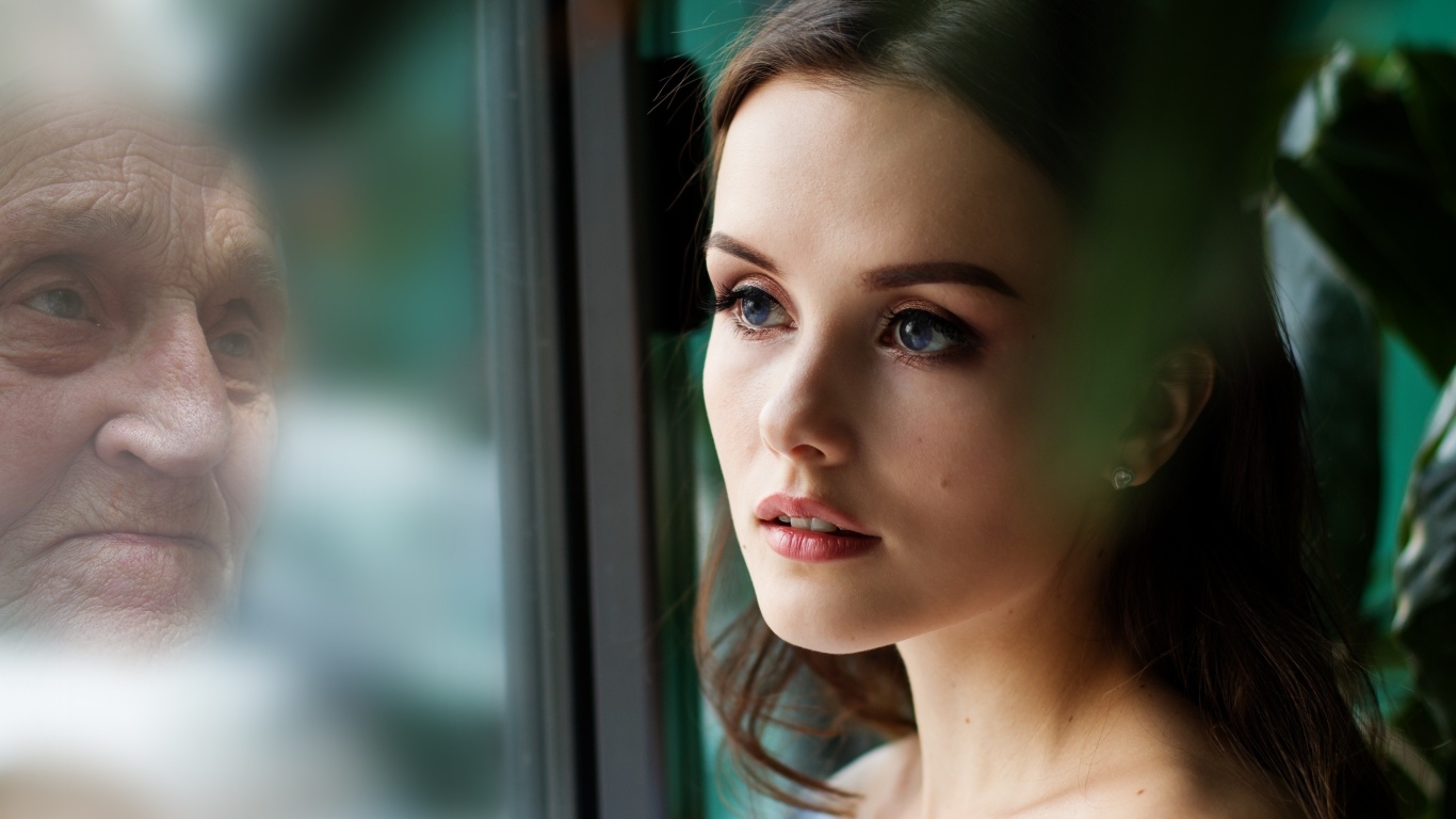 Девушка смотрит на свое отражение в старости