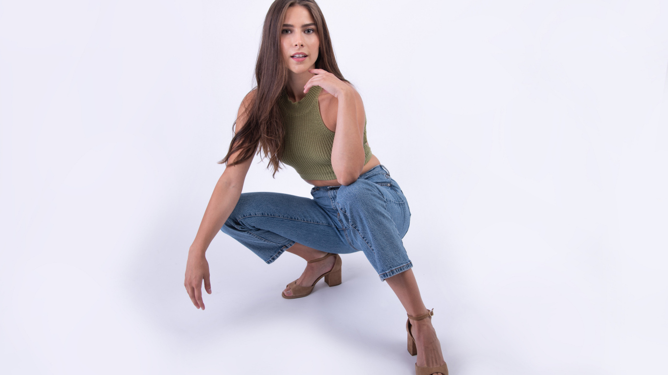 Девушка сидит на корточках на белом фоне