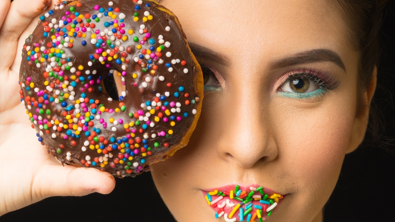 Девушка с пончиком в шоколаде в руках