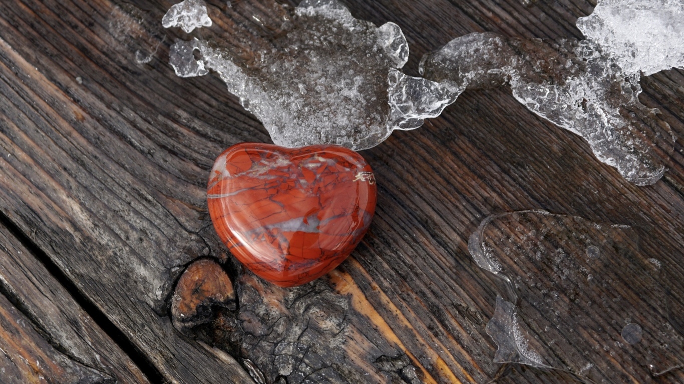 Сердце из камня на деревянной лавке с тающим снегом