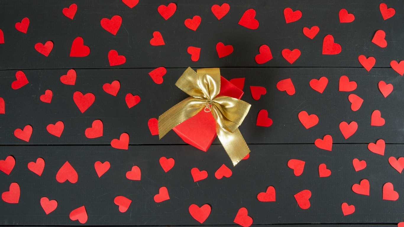 Много маленьких бумажных сердечек с подарком на столе