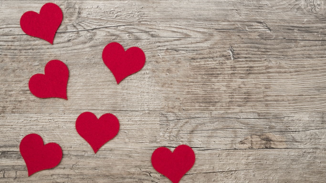 Маленькие красные сердечки на деревянном фоне