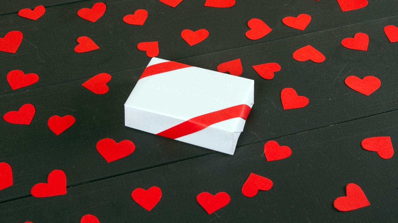 Белая коробка с маленькими бумажными сердечками на столе