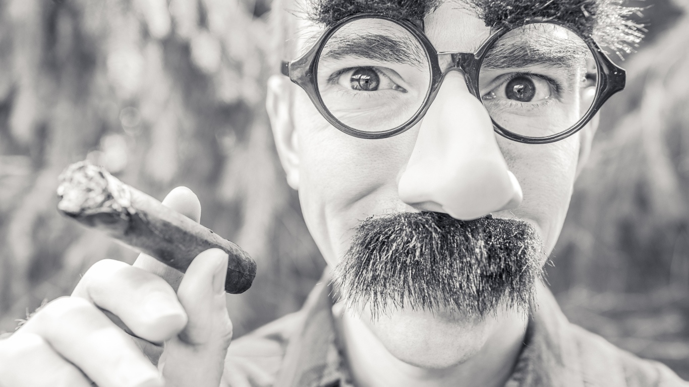 Мужчина в очках с сигарой в руке