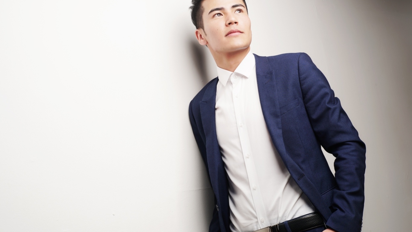 Молодой мужчина в костюме у стены