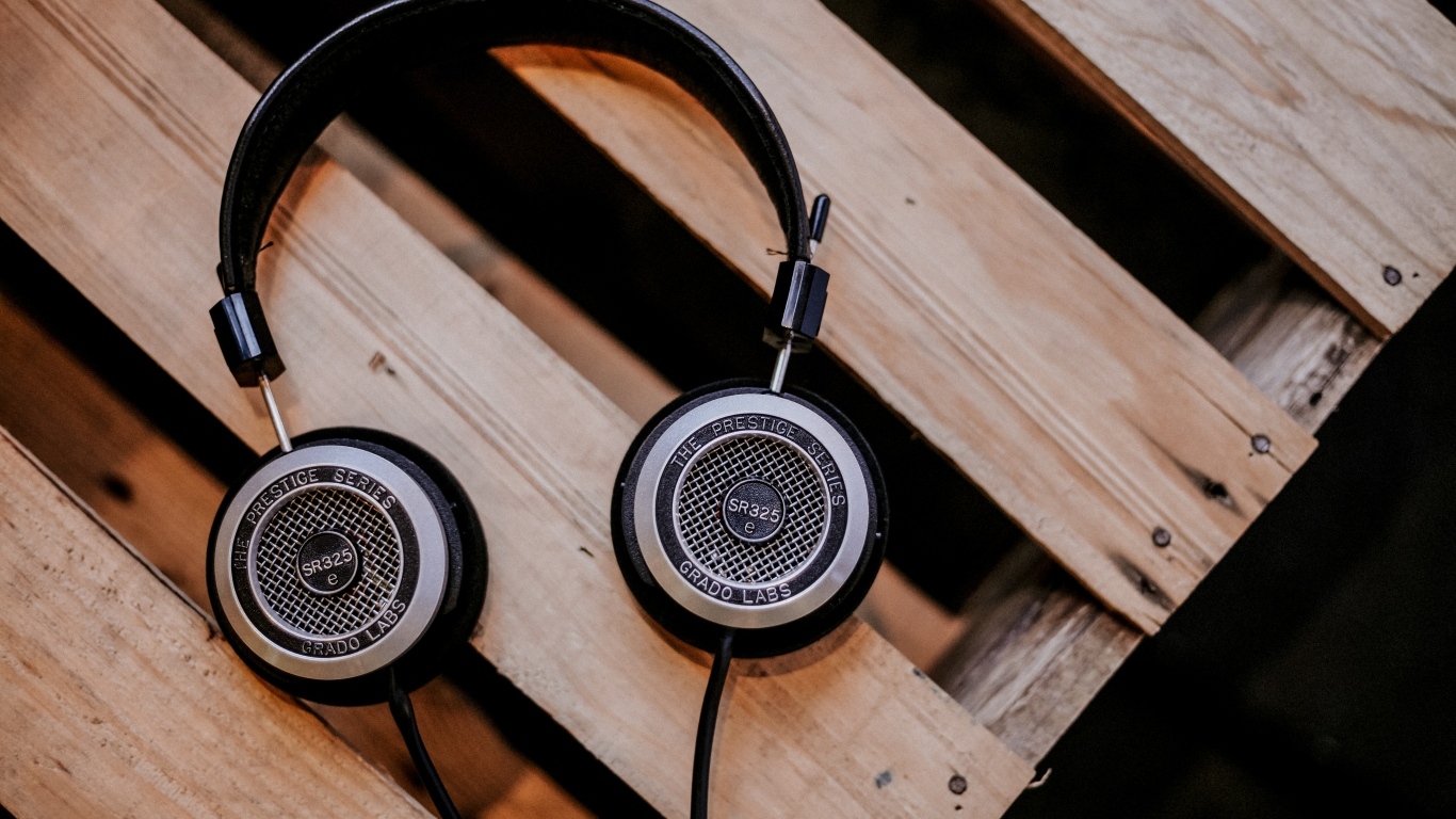 Старые наушники лежат на деревянной лавке