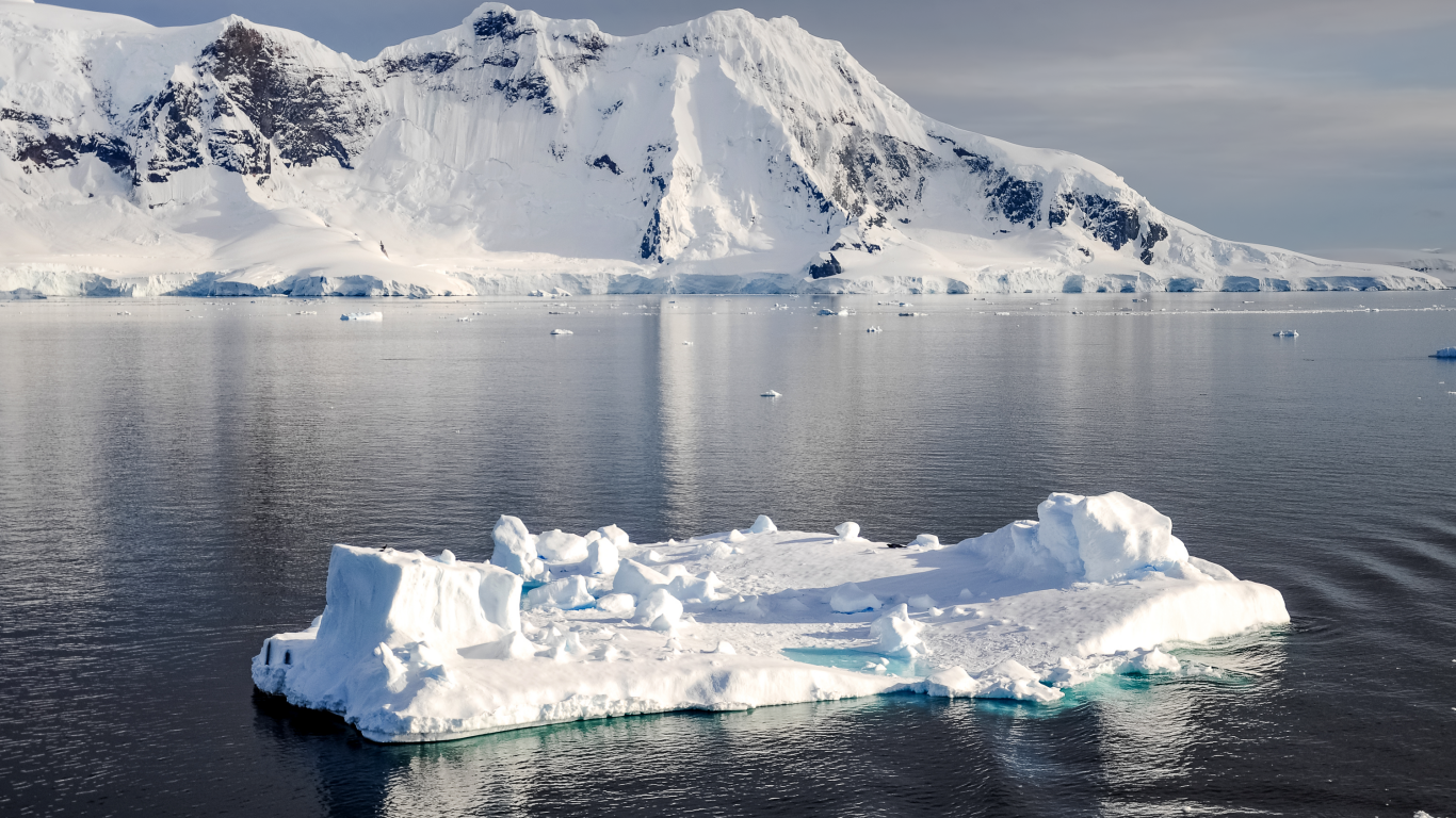Холодный айсберг в воде у заснеженных гор, Антарктика